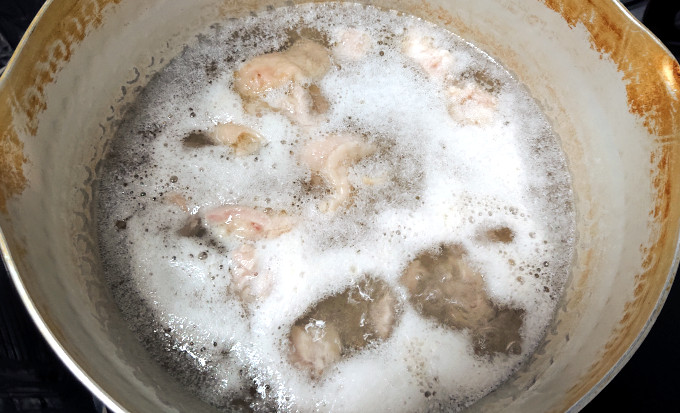 鍋を満たす鶏肉のアク