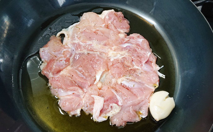 フライパンに入った鶏もも肉とニンニク